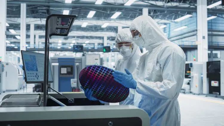 Semiconductor Production At Electronics Manufacturing Facility: Two Specialists In Sterile Suits Taking Out Silicon Wafer From Soldering Jet Printer And Inspecting. Engineers Making Computer Hardware
